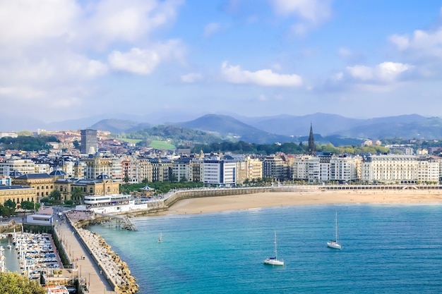 Piękny widok zachodzącego słońca na piaszczystą plażę i przystań w centrum miasta Donostia San Sebastian