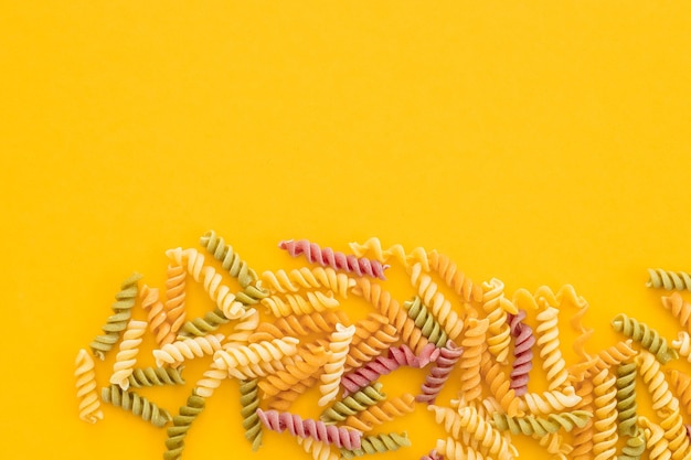 Piękny włoski niegotowany kolorowy makaron farfalle zbliżenie na żółtym tle poziomy widok z góry