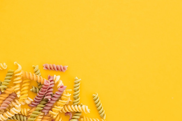 Piękny włoski niegotowany kolorowy makaron farfalle zbliżenie na żółtym tle poziomy widok z góry