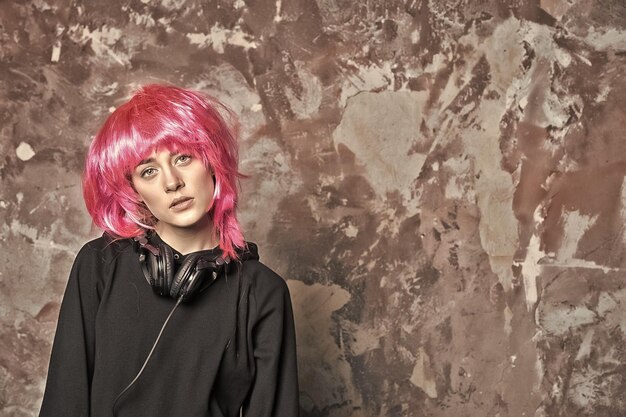 Piękny wygląd fryzura vintage filtr Kobieta w różowej perukie włosy noszą czarny sweter Dziewczyna z słuchawkami na abstrakcyjnej ścianie Koncepcja stylu mody Technologia muzyczna rozrywka przestrzeń kopiowania