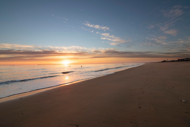 Piękny zachód słońca na plaży Mazagón Hiszpania W tle sylwetki dwóch surferów