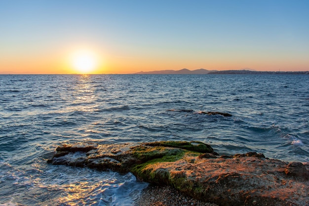 Piękny zachód słońca nad brzegiem skalistej morskiej plaży seascape