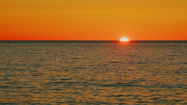 Piękny zachód słońca nad morzem promienie słoneczne migoczące w fali na powierzchni wody naturalne niebo odbija się w