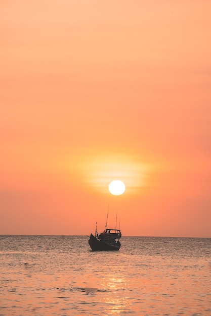 Piękny zachód słońca Tropikalny pejzaż morski z łodzią na piaszczystej plaży przy zachmurzeniu