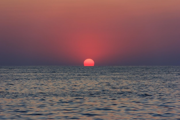 Piękny zachód słońca z czerwonym słońcem chowającym się za horyzontem w morzu