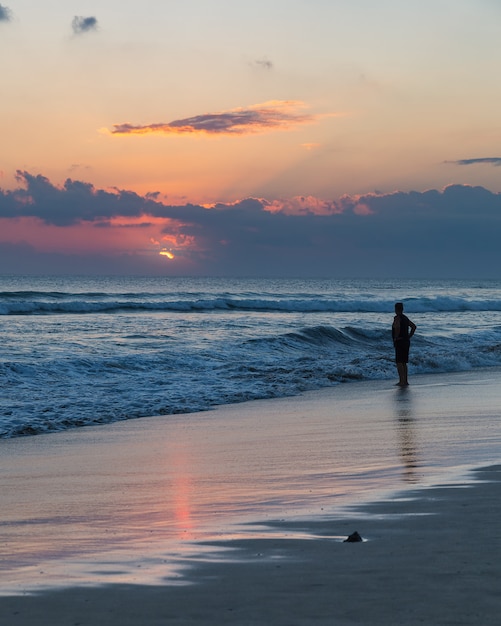 Piękny zmierzch i sylwetka mężczyzna na Seminyak plaży, Bali