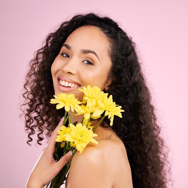 Pielęgnacja skóry twarzy i piękno kobiety z kwiatami w studiu izolowanym na różowym tle Portret uśmiechu i naturalnego modelu z roślinnymi kosmetykami kwiatowymi lub organicznymi zabiegami dla zdrowej estetyki skóry