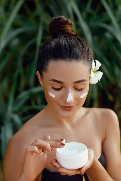 Pielęgnacja skóryBeauty Woman Concept Młoda ładna kobieta trzyma krem kosmetyczny
