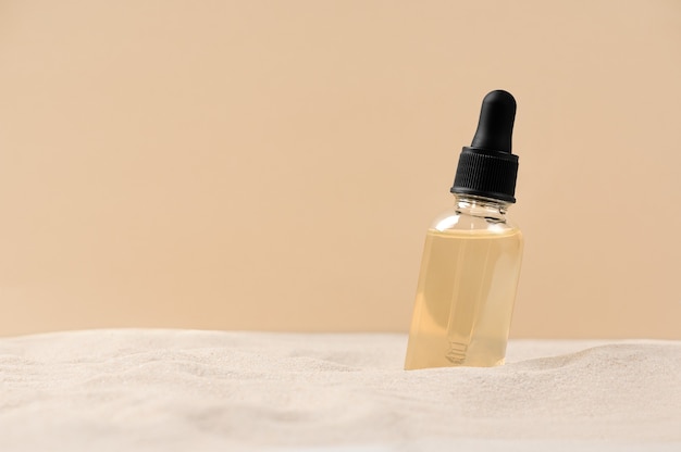 Pielęgnacja Z Serum Kosmetycznym Do Twarzy. Szklana Butelka Z Pipetą Na Naturalnym Tle Z Piaskiem. Produkt Do Pielęgnacji Skóry Suchej. Olejek Eteryczny Do Nawilżania Skóry Ciała. Skopiuj Miejsce.