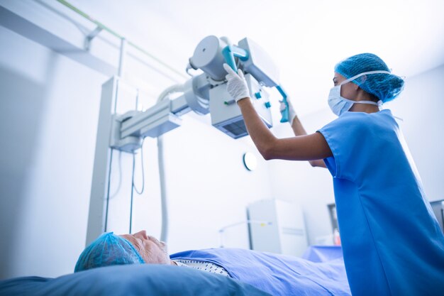 Pielęgniarka dostosowuje aparat rentgenowski nad pacjentem