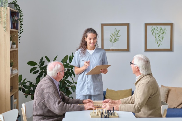 Pielęgniarka rozmawiająca ze starszymi mężczyznami w domu opieki