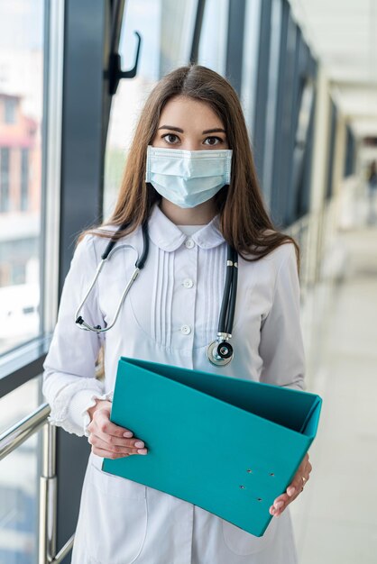 Pielęgniarka w kolorze niebieskim w masce medycznej zapisuje informacje o pacjencie