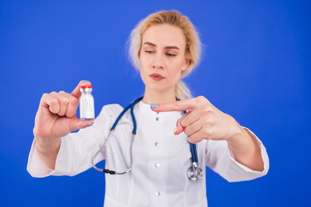 Zdjęcie pielęgniarka z butelką białego proszku na niebieskim tle