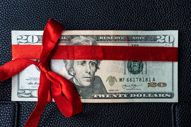 Pieniądze jako prezent urodzinowy z czerwoną wstążką, prezent w dolarach
