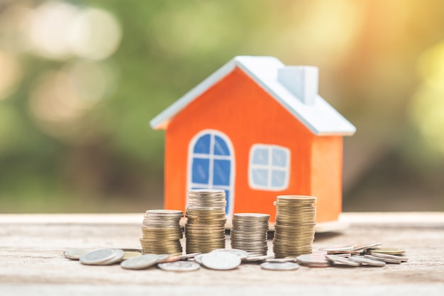 Pieniądze w modelu domu i monety, inwestycje hipoteczne i nieruchomościowe.