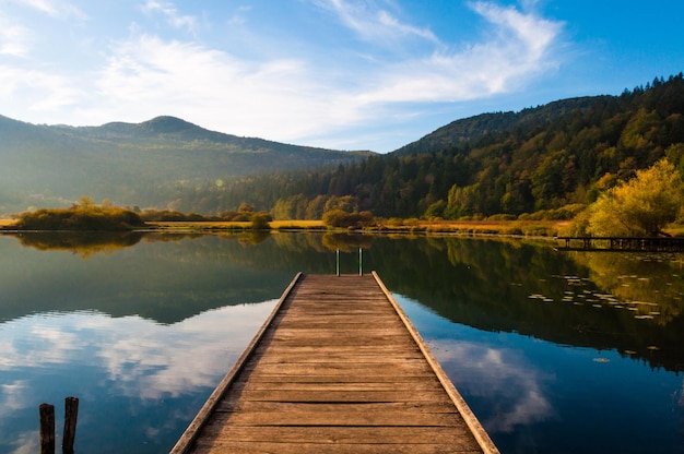 Pier przy spokojnym jeziorze na tle nieba jesienią