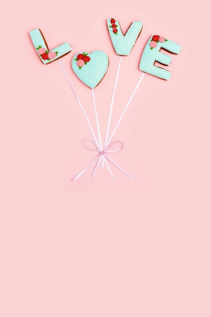 Piernikowe serce i słowa miłość z ciasteczek z lukrem na pastelowym różowym papierze Walentynki backgro