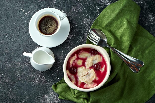 Pierogi z wiśniami w sosie i kwaśną śmietaną na ciemnym tle Ukraiński deser varenyky