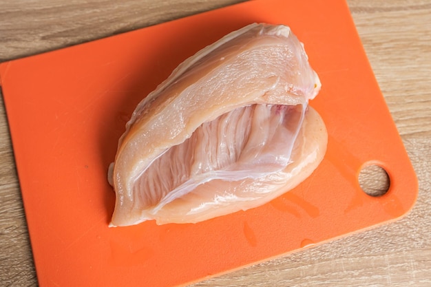Zdjęcie pierś z kurczaka na czerwonej desce do krojenia