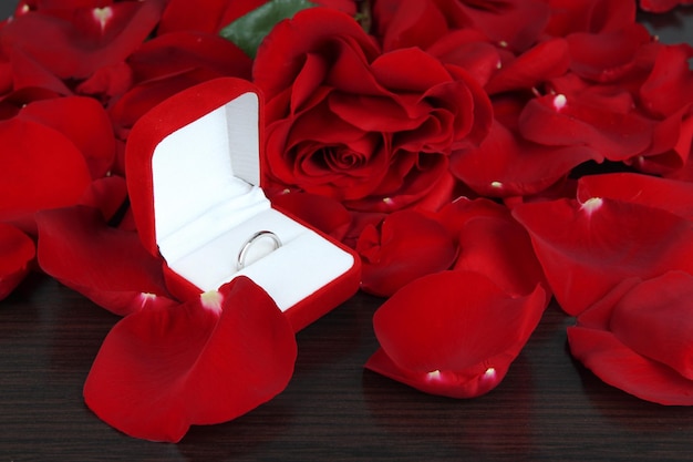 Pierścień otoczony płatkami róż na drewnianym stole z bliska