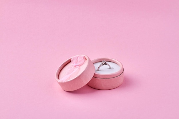 Pierścionek zaręczynowy w różowym pudełku na różowym tle