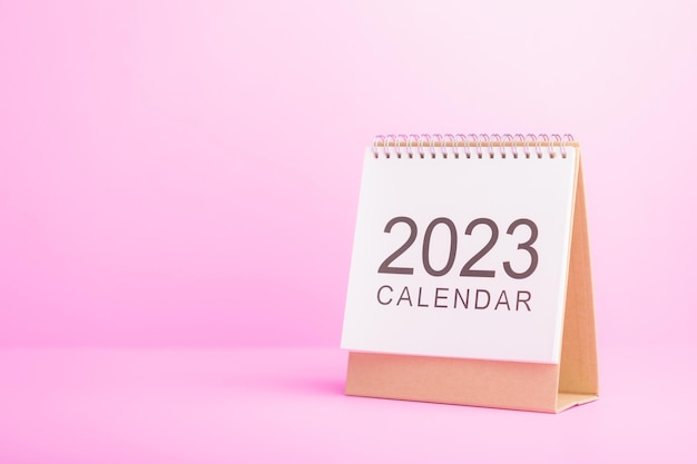 Zdjęcie pierwsza strona białego nowego kalendarza biurkowego 2023 na różowym tle 2023 koncepcja planowania i planowania