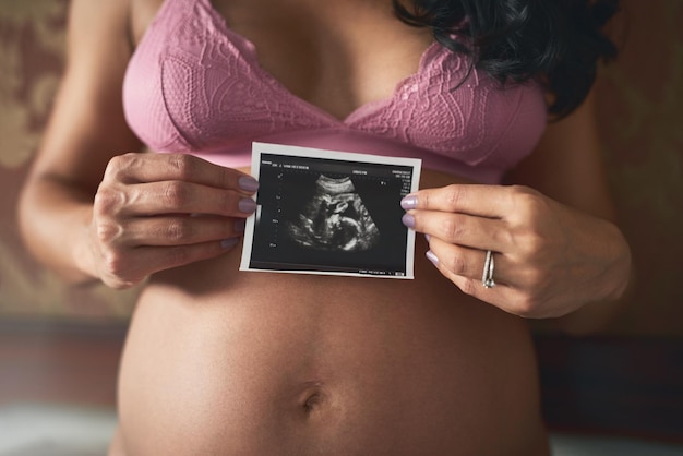 Pierwsze zdjęcie mojego dziecka Przycięte zdjęcie nierozpoznawalnej kobiety w ciąży stojącej w swojej sypialni w domu