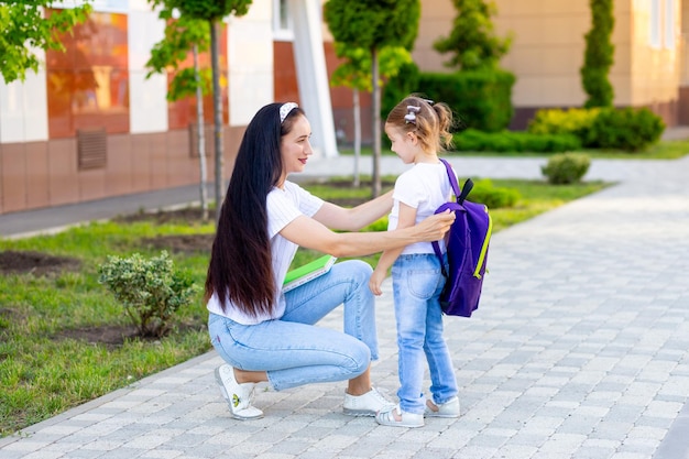 Pierwszy dzień szkoły matka prowadzi małą dziewczynkę do pierwszej klasy trzymając ją za ręce koncepcja jest z powrotem do szkoły