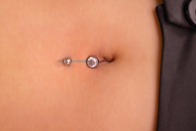 Pierwszy piercing zakładający kolczyki na pępku kobiecy piercing