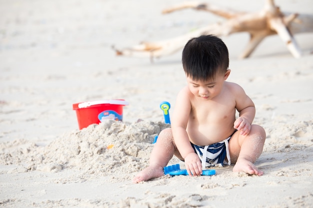 Pierwszy roczniak chłopiec bawić się piaskiem, Bierze dziecka plażowy pojęcie