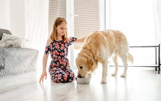 Pies golden retriever jedzący jedzenie z ładną dziewczyną w domu