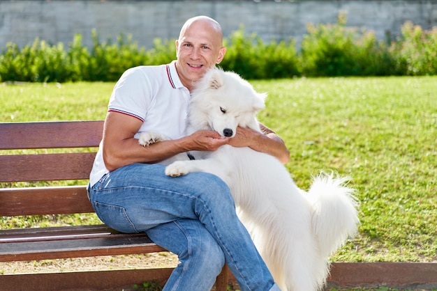 Zdjęcie pies rasy samoyed ze swoim właścicielem w parku bawi się razem