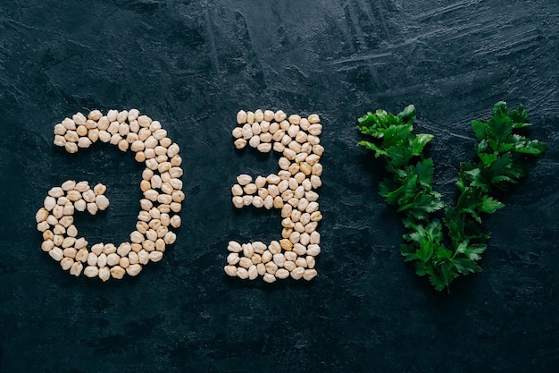 Pietruszka i suche garbanzo w formie liter oznaczających wegetariańskie wegetariańskie na białym tle na ciemnym tle Organiczny produkt białkowy Wegańskie jedzenie