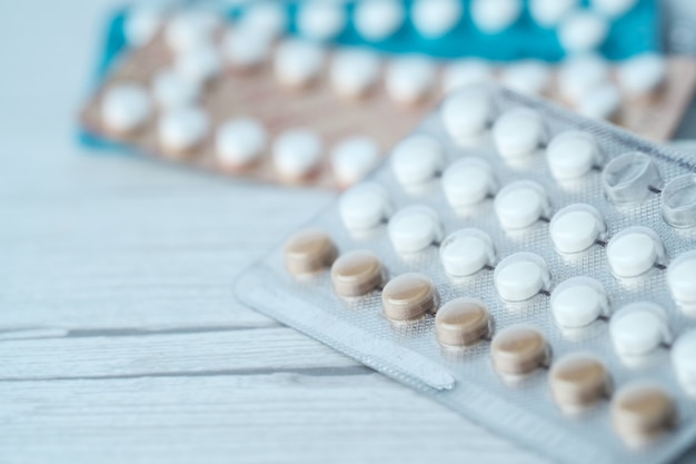 Pigułki antykoncepcyjne na drewnianym stole, z bliska.