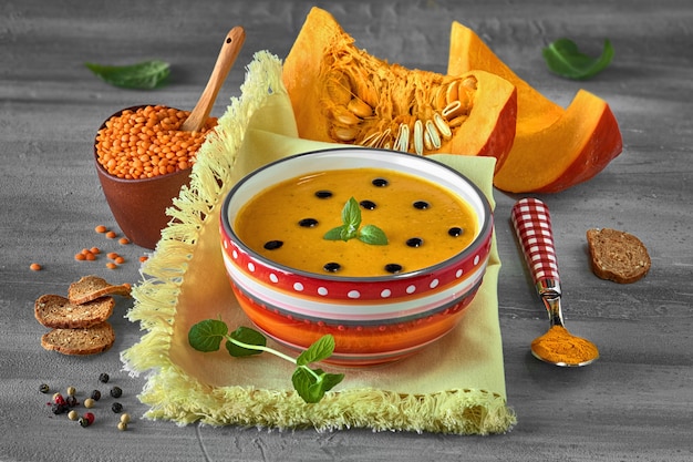Pikantna zupa dyniowa z czerwoną soczewicą i kurkumą podawana z liśćmi mięty i kroplami octu balsamicznego