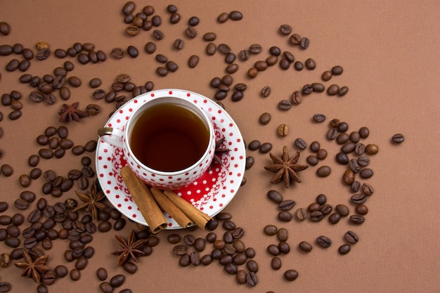Pikantny kubek czarnej kawy polka dot i ziaren kawy bałagan na brązowym tle
