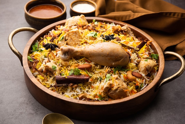 Pikantny kurczak Biryani w stylu restauracyjnym podawany z Raita i Salan, popularnym indyjskim lub pakistańskim nie wegetariańskim jedzeniem