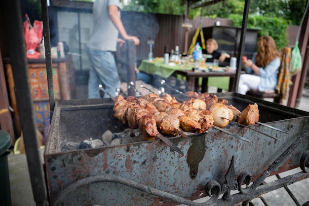 Piknik BBQ z kebabami i mięsem na otwartym ogniu w letni dzień na podwórku prywatnego domu