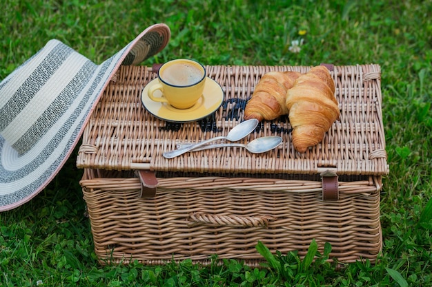 Piknik w parku na trawie wiklinowy kosz świeże rogaliki i kawa