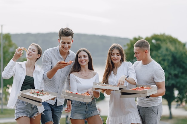 Piknikowi przyjaciele z pizzą i napojami, słoneczny dzień, zachód słońca, towarzystwo, zabawa, pary i mama z dzieckiem