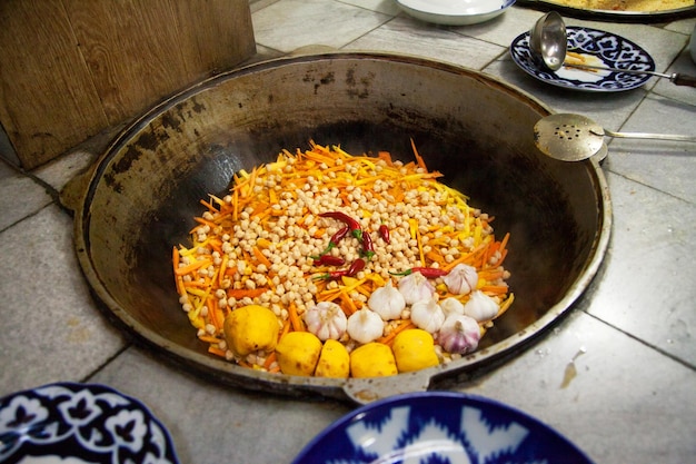 Zdjęcie pilaw z ryżową pigwą mięsną i ciecierzycą gotuje się w dużym kotle w bucharze w uzbekistanie