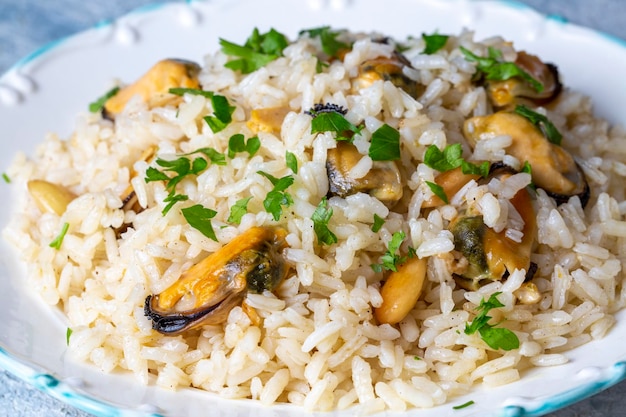 Pilaw z ryżu małży. Ryż z małżami na małym białym talerzu na ceramice. (nazwa turecka; midyeli pilaw)
