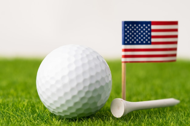 Piłka golfowa z flagą USA i tee na zielony trawnik