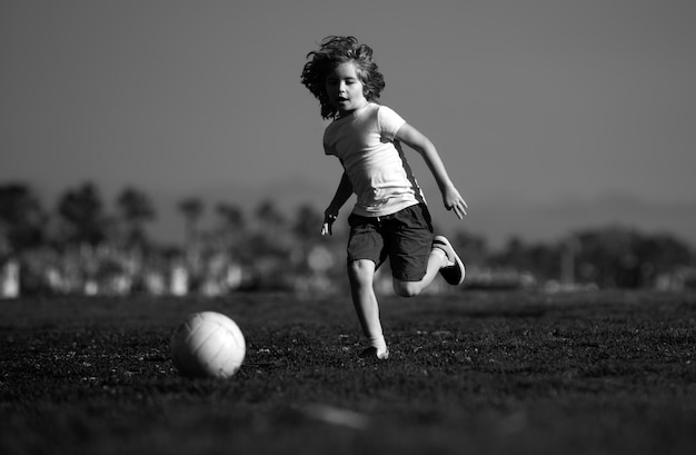 Piłka nożna dzieci chłopiec gra w piłkę nożną na świeżym powietrzu młody chłopiec z piłką nożną robi kopnięcie piłki nożnej