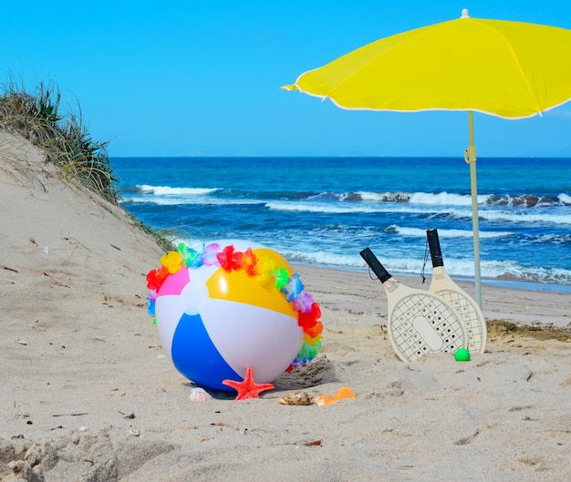 Piłka plażowa z rakietami na naszyjnik i parasolem nad morzem