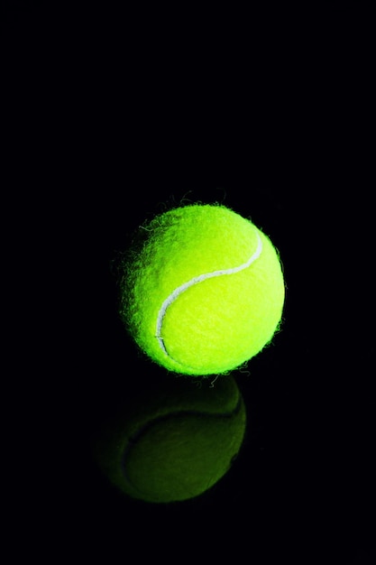 Piłka tenisowa na czarnym tle z dramatycznym oświetleniem