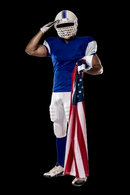 Piłkarz w niebieskim mundurze, salutując z amerykańską flagą, na czarnej ścianie