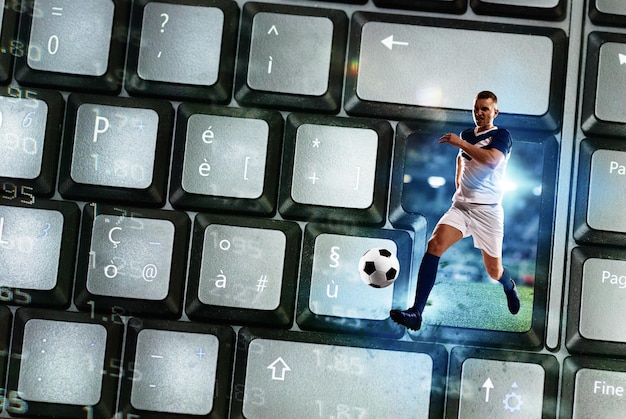 Zdjęcie piłkarz wychodzi z klawiatury komputera jako koncepcja przesyłania strumieniowego piłki nożnej