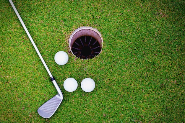 Piłki golfowe i kij golfowy na zielonej trawie