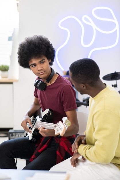 Pilny facet patrzący na swojego nauczyciela muzyki podczas gry na gitarze